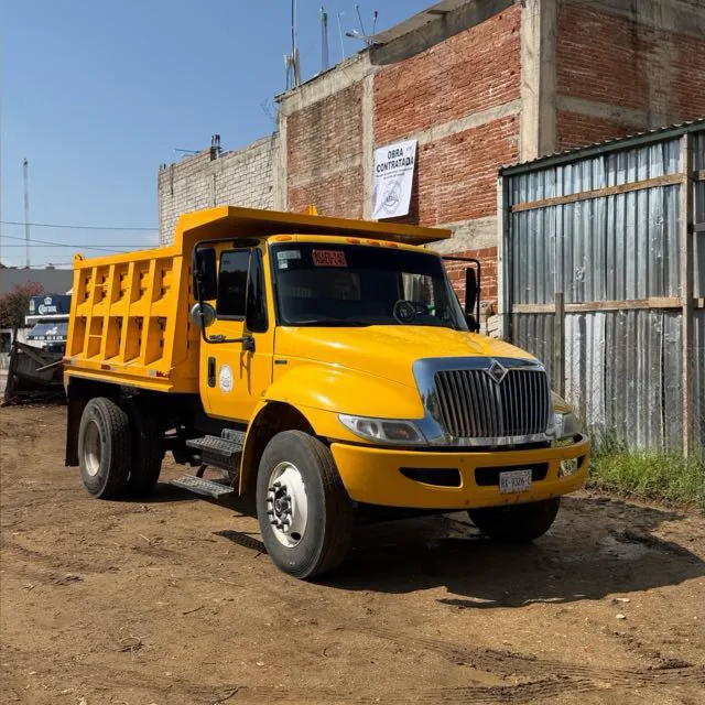Camión de volteo amarillo de Materiales Granada estacionado en un terreno de obra